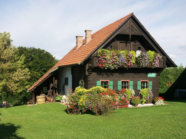 Das Bild zeigt das Heimatmuseum, das in einem alten Haus mit teilweiser Holzfassade untergebracht ist. Es ist mit zahlreichen Blumen in verschiednen Farben geschmückt