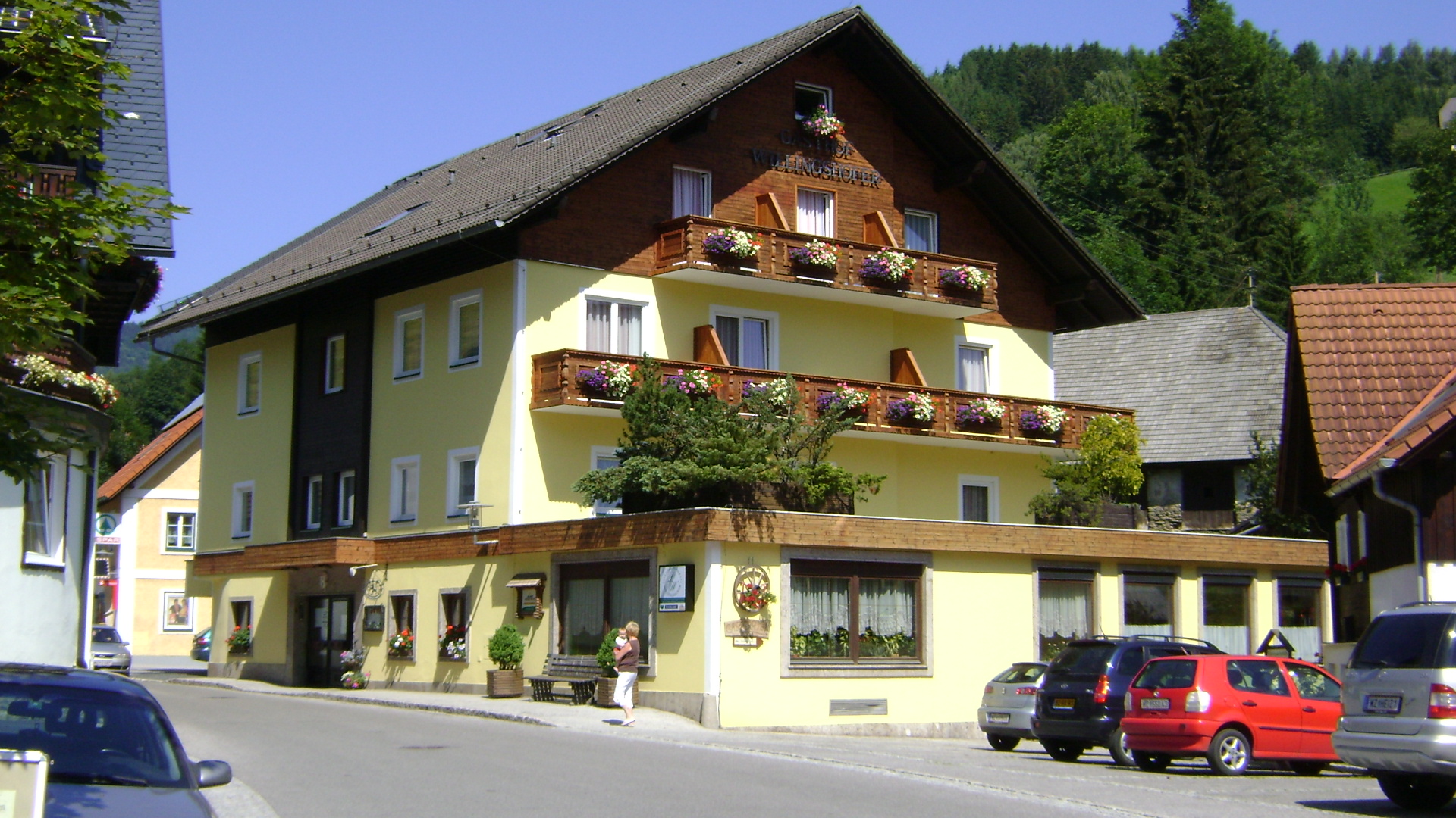 Gasthof Willingshofer im Gasener Zentrum. Ein viergeschoßiger Vertreter der Lederhosenarchitektur in zartgelb mit Balkonen und Verziehrungen aus Holz