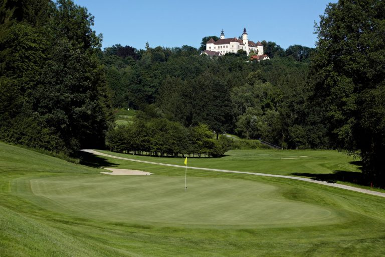 Das Bild zeigt einen Golfplatz mit dem Schloss Freiberg im Hintergrund auf einem Hügel