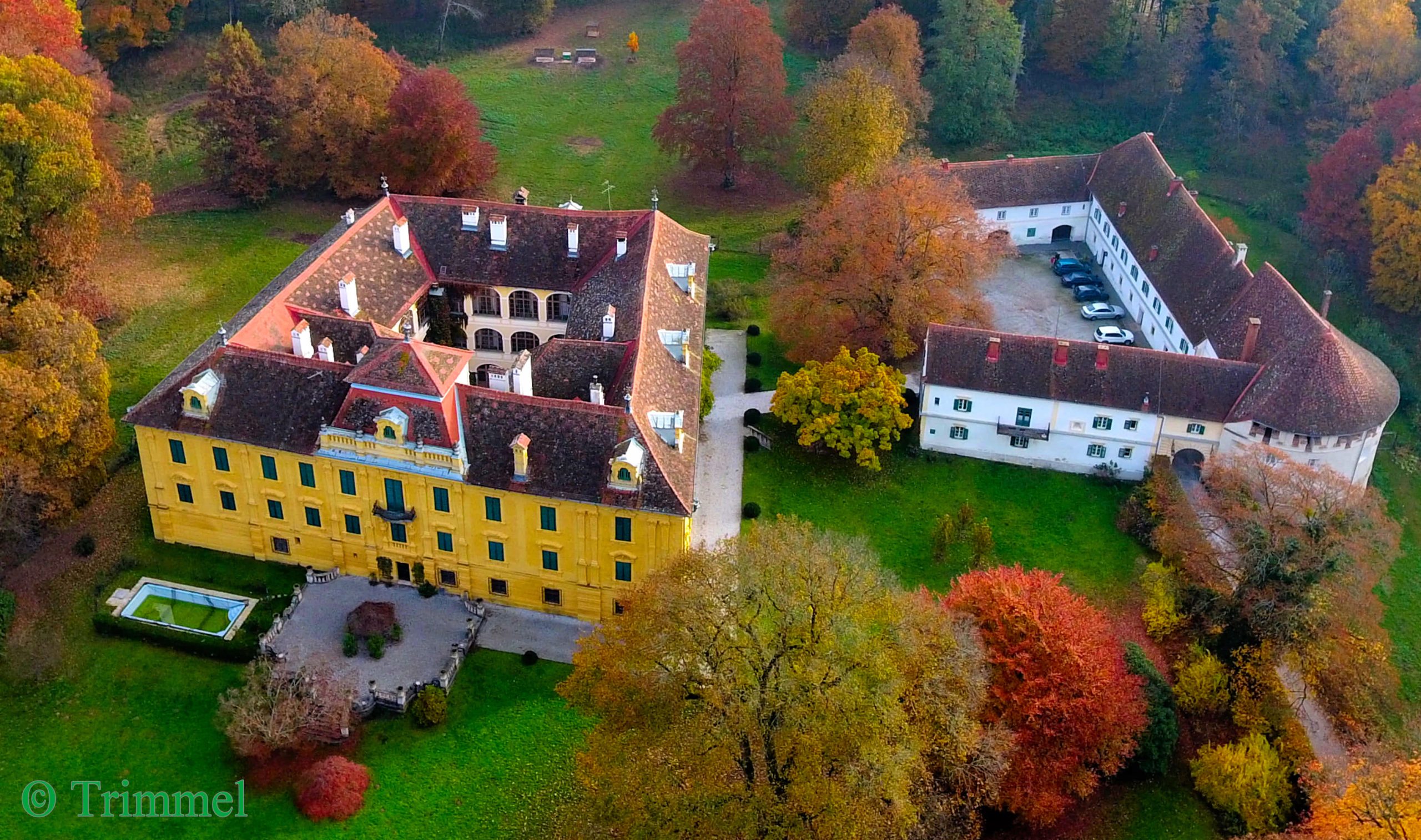 Luftaufnahme des aus zwei Gebäuden bestehenden Schlosses Neudau. Es liegt mitten im Grünen