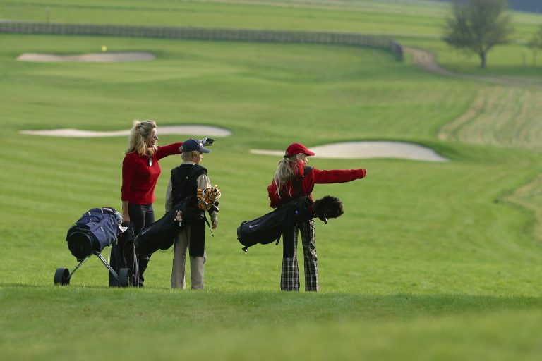 Drei Golfspielende zeigen in eine Richtung.