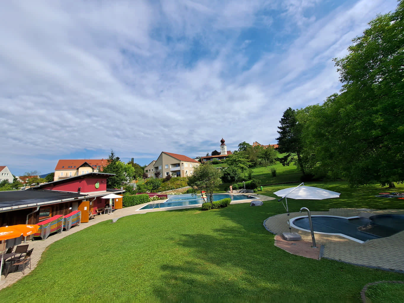 Freibad Puch mit zwei Becken, Liegewiese mit einigen großen Bäumen und einem kleinen Bistro. Auch Liegen stehen zu Verfügung