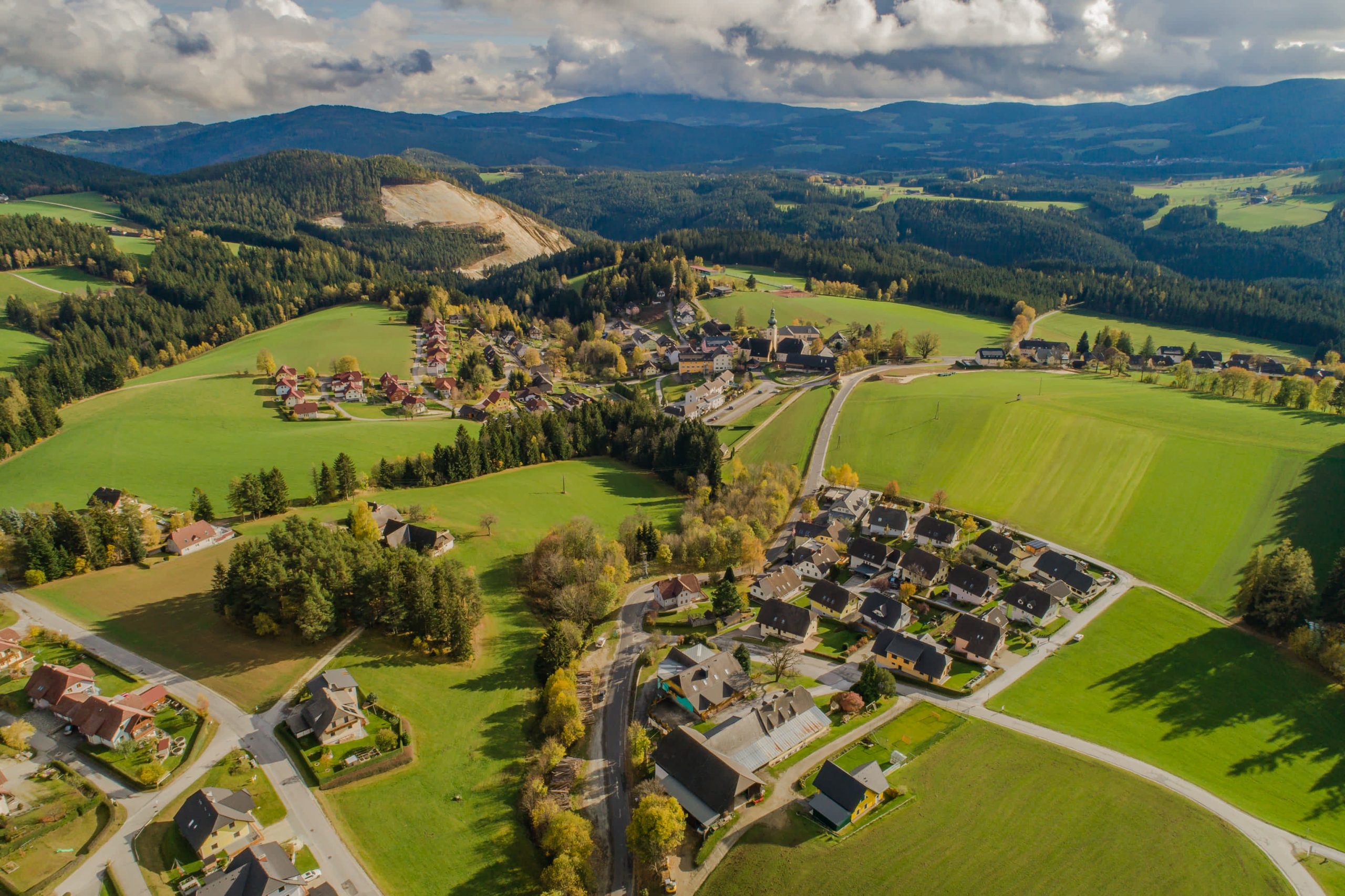 Luftaufnahme von St. Jakob im Walde. Rund um den Ortskern finden sich Wiesen, Wälder sowie ein altes Steinbruch