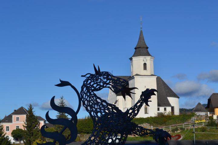 Aufnahme der Kirche in St. Kathrein mit Skulptur des steirischen Panthers im Vordergrund