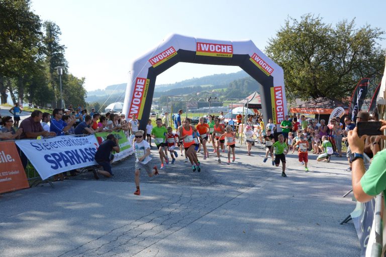 Das Bild zeigt ein Laufevent für Groß und Klein in Vorau. Zentral im Bild befindet sich der Zielbogen